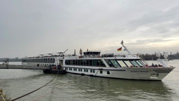 Am Rheinufer liegt ein Kreuzfahrtschiff an einem von sechs Anlagern, die mit einer Landstromanlage ausgestattet worden sind