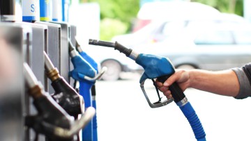 Person nimmt Zapfhahn aus der Tanksäule