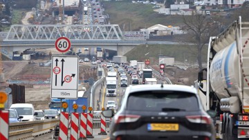 Eine Autobahnbaustelle an der A8 bei Pforzheim von Anfang 2025. Dichter Verkehr mit Autos und Lkw fließt in beide Richtungen mit gelben Fahrstreifen. Warnbaken und ein Hinweisschild mit Fahrstreifen, Grenze der Fahrzeugbreite und Tempolimit sind im Vorder