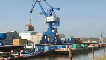 Ein Kran hebt  im Elbhafen Aken Container von einem Prahm