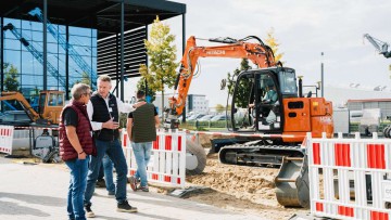 Zwei Männer diskutieren vor einer Aktionsfläche mit Kran