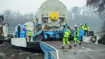 Arbeiter in gelber Warnkleidung überwachen den GST: Über die RoRo-Rampe rollte der SPMT mit dem Generator aus dem Schiff aus und fuhr direkt weiter durch die Stadt Mako bis zum Umladeplatz.