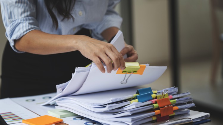 Geschäftsfrau Hände arbeiten in Stapeln von Papierakten zum Suchen und Überprüfen von unfertigen Dokumenten erreicht auf Ordnerpapieren 
