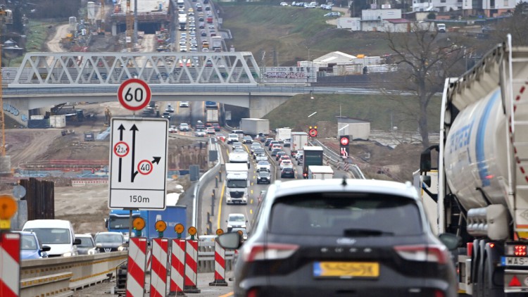 Eine Autobahnbaustelle an der A8 bei Pforzheim von Anfang 2025. Dichter Verkehr mit Autos und Lkw fließt in beide Richtungen mit gelben Fahrstreifen. Warnbaken und ein Hinweisschild mit Fahrstreifen, Grenze der Fahrzeugbreite und Tempolimit sind im Vorder