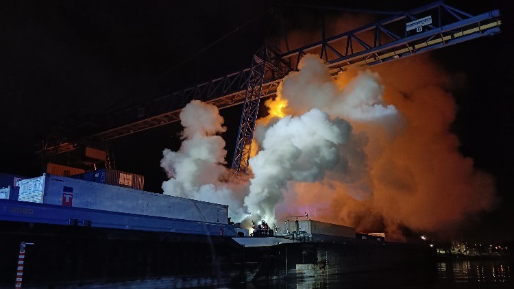 Brandqualm über nächtlichem Containerschiff