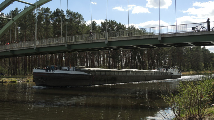 Ein Binnenschiff unter einer Fußgängerbrücke