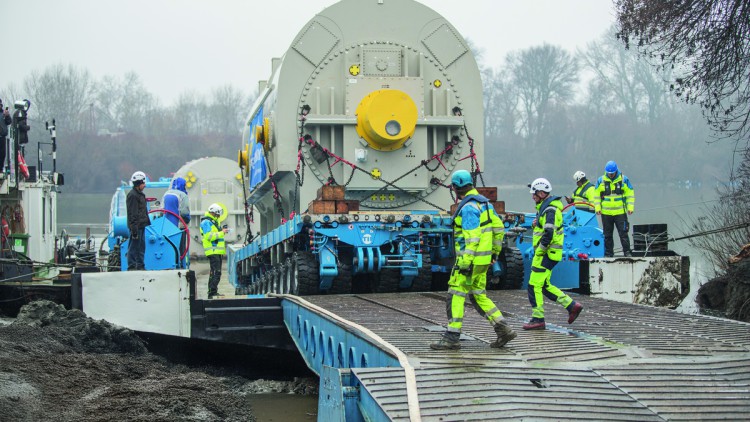 Arbeiter in gelber Warnkleidung überwachen den GST: Über die RoRo-Rampe rollte der SPMT mit dem Generator aus dem Schiff aus und fuhr direkt weiter durch die Stadt Mako bis zum Umladeplatz.